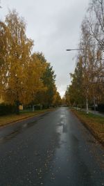 Road amidst trees against sky during autumn