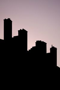 Low angle view of silhouette buildings against clear sky