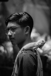 Side view of man with chameleon on shoulder
