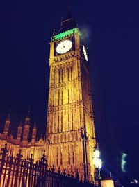 Low angle view of clock tower at night