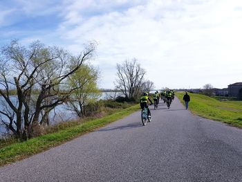 Rear view of man riding bicycle on road against sky