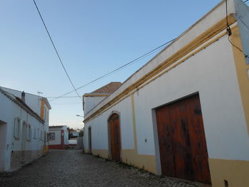 Street amidst buildings against clear blue sky