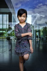 Portrait of smiling girl standing against glass