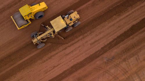 Aerial view yellow excavator building a highway, road grader heavy earth moving, bulldozer working