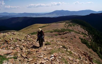 High angle view of man hiking on mountain against sky