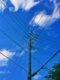 Low angle view of electricity pylon against cloudy sky