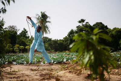 Woman standing by plants on field against sky