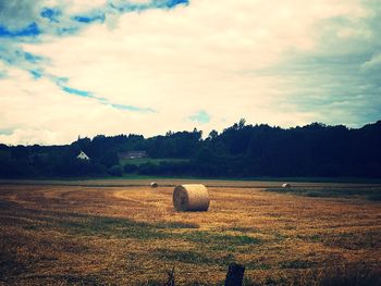 Hay bales on field against sky