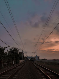 Railroad tracks against sky at sunset