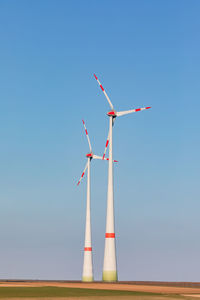 Two wind turbines dominate nature in rural germany against clear sky