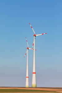Two wind turbines dominate nature in rural germany against clear sky