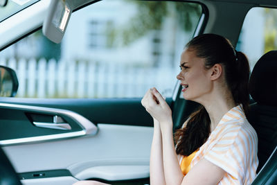 Young woman using mobile phone while sitting in car