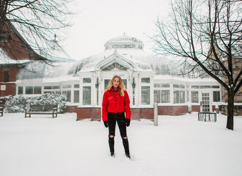 Full length portrait of young woman standing on snow covered landscape