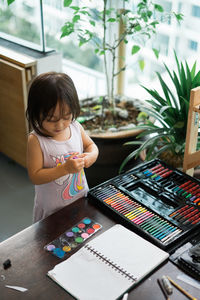 High angle view of girl by art and craft equipment on table