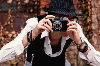 Close-up of photographer using analog photo camera while taking picture outdoors.