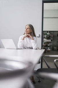 Senior businessswoman sitting at conference table with laptop
