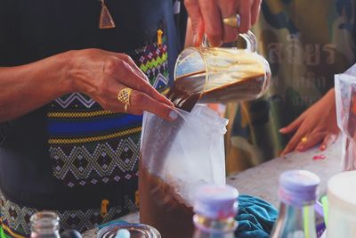 Midsection of woman pouring coffee in plastic bag at market stall