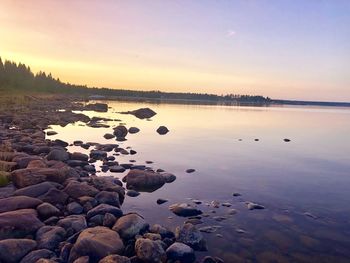 Scenic view of rocks in lake against sky during sunset