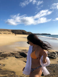 Woman standing at beach against sky