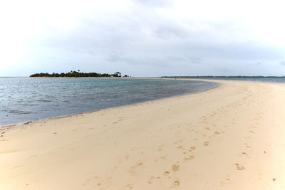 Scenic view of beach against cloudy sky