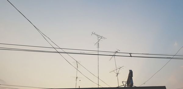 Low angle view of silhouette electricity pylon against clear sky