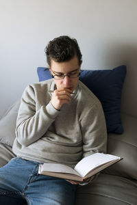 Young man using phone while sitting on sofa at home