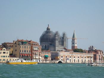 San marco campanile and incomplete santa maria della salute by canal against clear sky