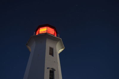 Low angle view of lighthouse against clear sky at night