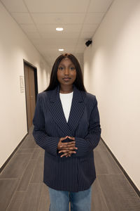 Portrait of young woman standing against wall