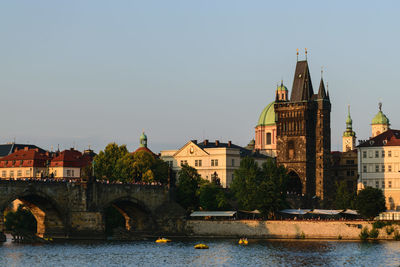 Arch bridge over river by buildings against sky in city