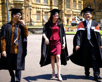 People in graduation gown walking on street