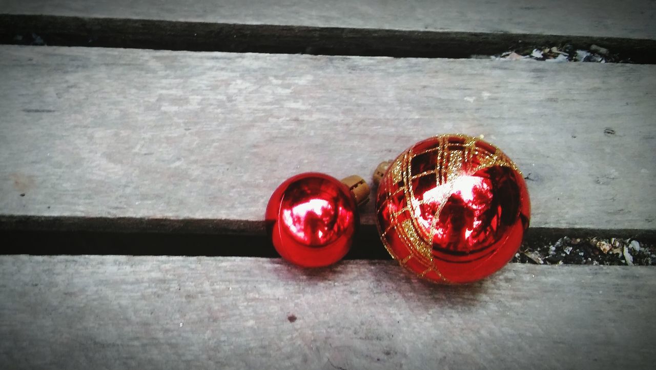 red, still life, indoors, close-up, wood - material, wall - building feature, no people, christmas, ball, decoration, single object, floor, wooden, high angle view, flooring, table, toy, hanging, tradition, celebration