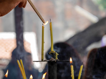 Cropped hand igniting candle at temple