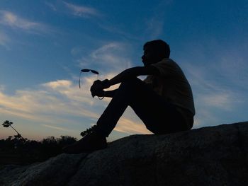 Low angle view of man photographing against sky