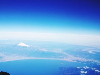 Aerial view of snowcapped mountains against blue sky