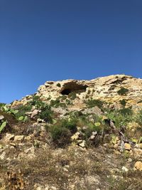 Low angle view of rocky mountain against clear blue sky