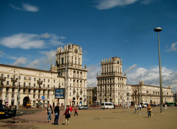 People in front of building against cloudy sky