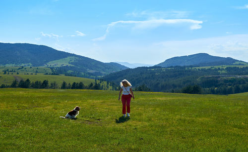 Rear view of man and daughter on mountain against sky
