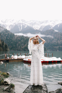 Woman standing by lake against mountain range