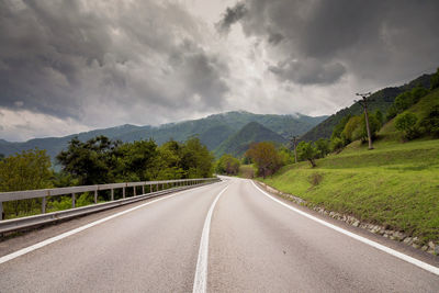 Road by mountains against sky