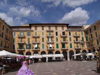 People in town square against cloudy sky