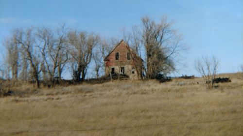 Close-up of abandoned house in field against clear sky