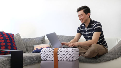 Man using laptop while sitting on sofa at home