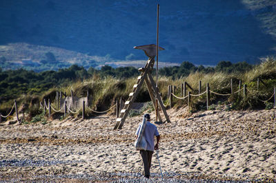 Rear view of man walking on beach against sky