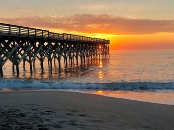 Pier over sea against sky during sunset