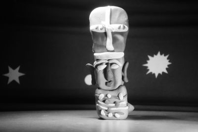 Close-up of human sculpture on table against black background