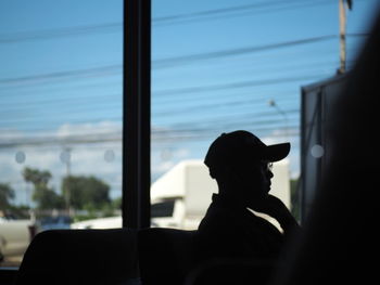 Rear view of silhouette woman looking through window