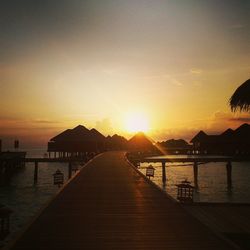 Silhouette pier over sea against sky during sunset