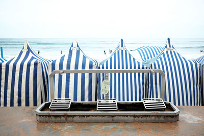 Beach cabins on beach against white sky