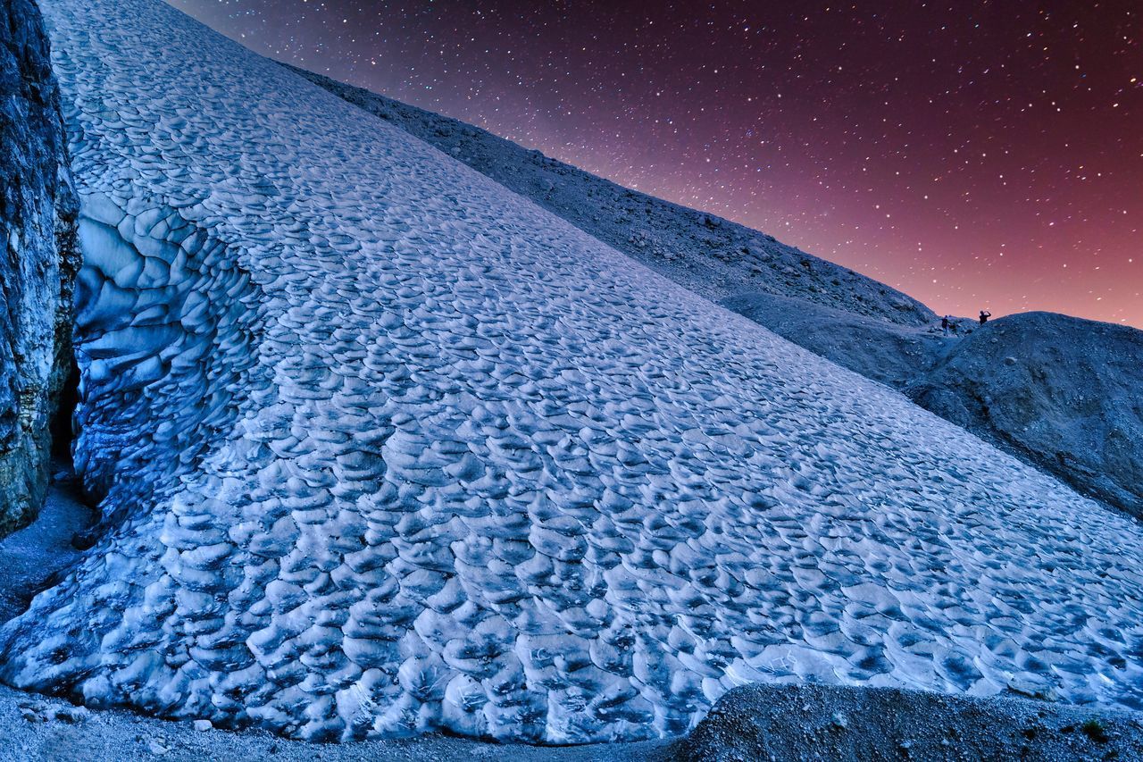 AERIAL VIEW OF SNOWCAPPED MOUNTAIN AGAINST SKY AT NIGHT